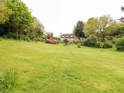 a field of grass with a house in the background at Flushing Meadow in Helston