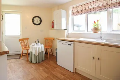 a kitchen with a sink and a table with chairs at Sunny Corner Cottage in Hayle