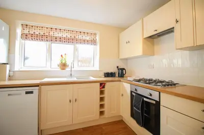 a kitchen with white cabinets and a sink and a window at Sunny Corner Cottage in Hayle