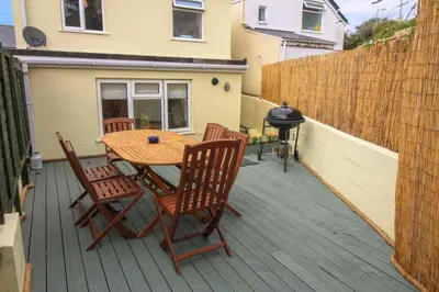 a wooden table and chairs on a deck at Sunny Corner Cottage in Hayle