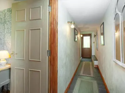 a hallway with a white door and a hallway with a table at Wheal Trenwith Cottage in St Ives