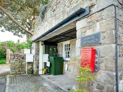 an old stone building with a green door and a red box at Wheal Trenwith Cottage in St Ives