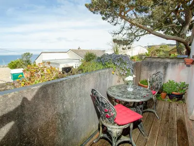 a patio with a table and chairs and the ocean at Wheal Trenwith Cottage in St Ives