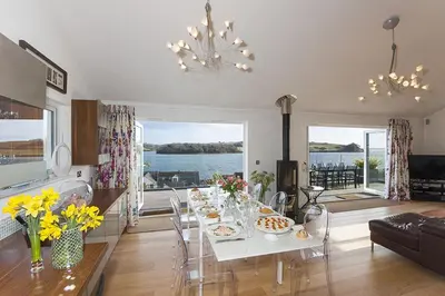 a kitchen and living room with a table with flowers on it at Dreamcatchers in Truro