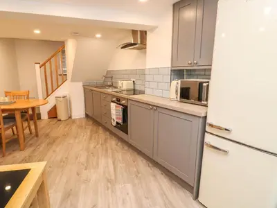 a kitchen with gray cabinets and a wooden floor at Blue Skies in Hayle