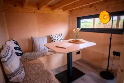a tiny house with a table and a couch at Luxury Glamping Cabin with Outdoor Bath on Cornish Meadow in Truro