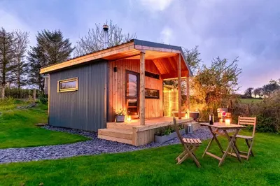 a small shed with a table in the grass at Luxury Glamping Cabin with Outdoor Bath on Cornish Meadow in Truro