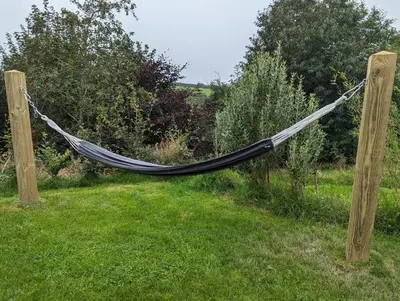 a hammock hanging from two wooden poles in a yard at Luxury Glamping Cabin with Outdoor Bath on Cornish Meadow in Truro