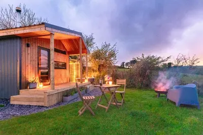 a small cabin with a table and chairs in the grass at Luxury Glamping Cabin with Outdoor Bath on Cornish Meadow in Truro