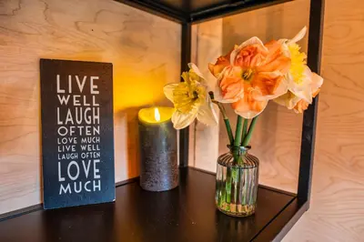 a table with a vase of flowers and a candle at Luxury Glamping Cabin with Outdoor Bath on Cornish Meadow in Truro