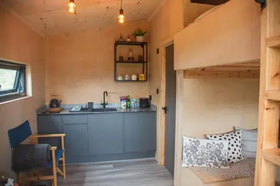 a tiny house with a kitchen and a loft bed at Luxury Glamping Cabin with Outdoor Bath on Cornish Meadow in Truro