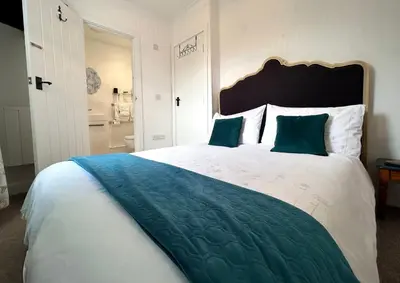 a bedroom with a large bed with green pillows at Britannia House Vintage B&B Cornwall in Helston