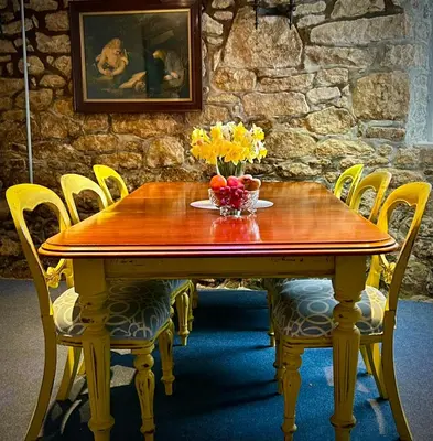 a wooden table with a bowl of fruit and flowers on it at Britannia House Vintage B&B Cornwall in Helston
