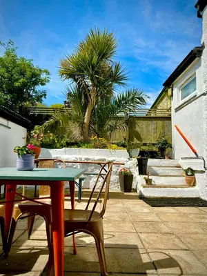 a patio with a table and chairs and a palm tree at Britannia House Vintage B&B Cornwall in Helston