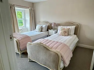 a bedroom with two beds and a chair at Britannia House Vintage B&B Cornwall in Helston