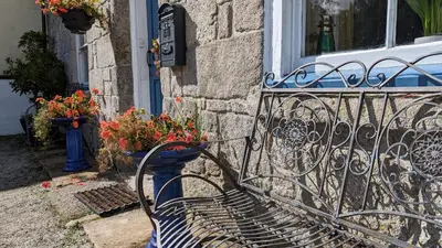 a black bench in front of a building with flowers at Britannia House Vintage B&B Cornwall in Helston