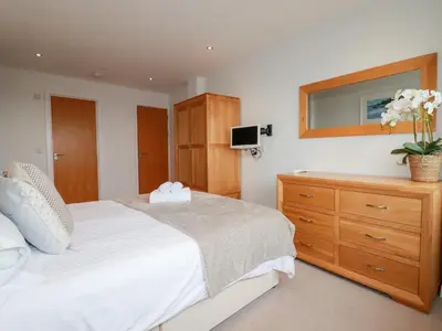 a bedroom with a bed and a dresser with a mirror at Fistral Pearl in Newquay