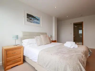 a bedroom with a large white bed and a night stand at Fistral Pearl in Newquay