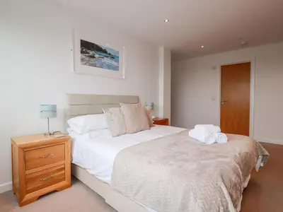 a bedroom with a large bed and a night stand at Fistral Pearl in Newquay