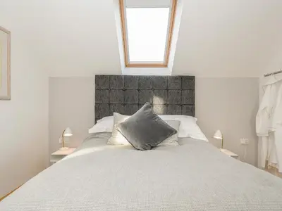 a white bedroom with a large bed with a window at Spires in Truro