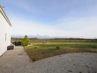 a view of a field with a house and a grass field at Spires in Truro
