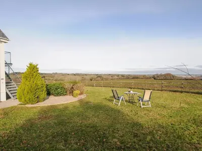 a patio with two chairs and a table in the grass at Spires in Truro