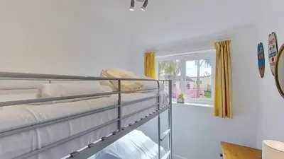 a bedroom with two bunk beds and a window at F11 Roslyn, Riviere Towans in Hayle