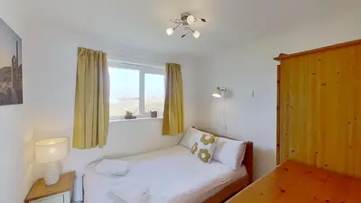 a small bedroom with a bed and a window at F11 Roslyn, Riviere Towans in Hayle