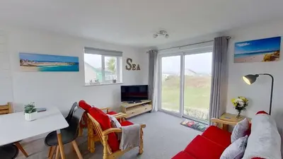 a living room with a red couch and a table at F11 Roslyn, Riviere Towans in Hayle