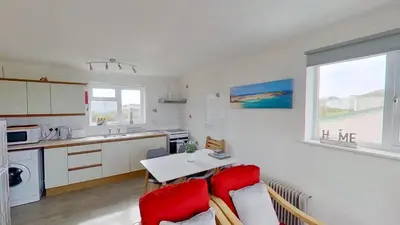 a kitchen with a couch and a table with red chairs at F11 Roslyn, Riviere Towans in Hayle