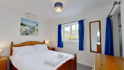 a bedroom with a bed with blue curtains and a window at F13 Trefusis, Riviere Towans in Hayle
