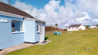 a blue house with a grass yard next to it at F13 Trefusis, Riviere Towans in Hayle