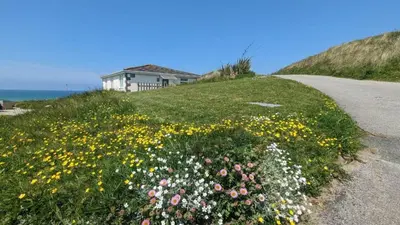 a house on the side of a hill with flowers at F13 Trefusis, Riviere Towans in Hayle