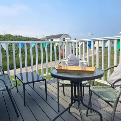 a table and chairs on a deck with a table and cups at F24 Glenara, Riviere Towans in Hayle