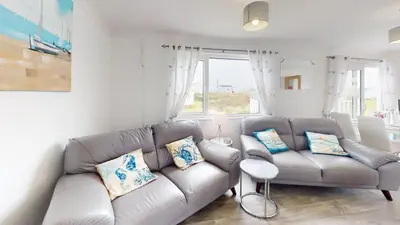 a living room with a gray couch with pillows at F24 Glenara, Riviere Towans in Hayle