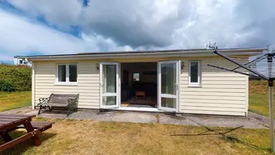 a small white house with a bench and a picnic table at F26 Porthia, Riviere Towans in Hayle