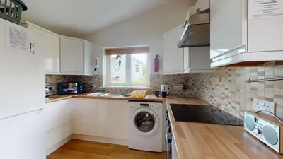 a kitchen with white cabinets and a washer at F26 Porthia, Riviere Towans in Hayle