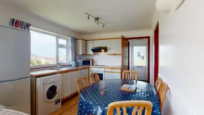a kitchen with a table and chairs and a kitchen with a sink at F30 Fernside, Riviere Towans in Hayle