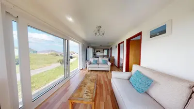 a living room with a couch and a large window at F30 Fernside, Riviere Towans in Hayle
