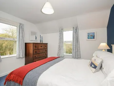 a white bedroom with a bed and a window at Kirland in Wadebridge