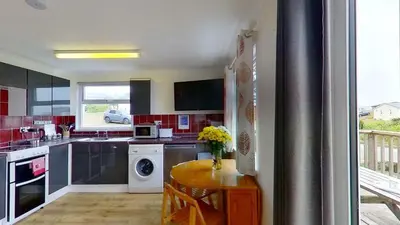 a kitchen with a washer and dryer and a table at F40 Bayford, Riviere Towans in Hayle