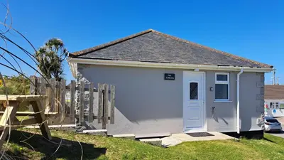 a small white house with a wooden fence at F49 Junesta, Riviere Towans in Hayle