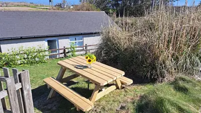 a wooden picnic table in the grass with a vase on it at F49 Junesta, Riviere Towans in Hayle
