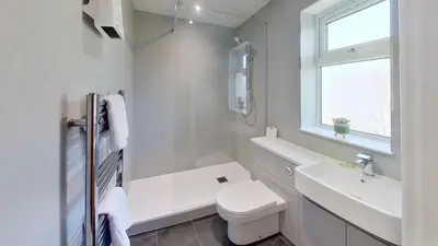 a white bathroom with a toilet and a sink at F49 Junesta, Riviere Towans in Hayle