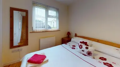 a bedroom with a white bed with red pillows at F43 Hazebrook, Riviere Towans in Hayle