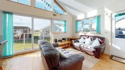 a living room with two leather couches and a large window at F43 Hazebrook, Riviere Towans in Hayle