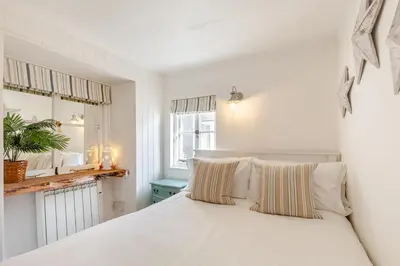 a white bedroom with a white bed with striped pillows at 2 Bed in St. Ives oc-p00568 in St Ives