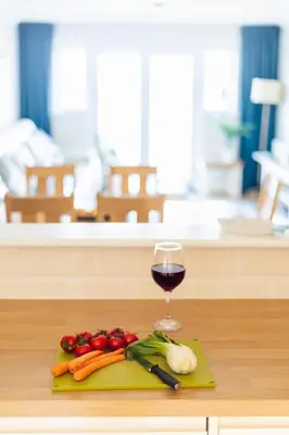 a glass of red wine and vegetables on a cutting board at Carbis Bay - Luxury 3 Bed Penthouse Apartment with Sea Views Parking Sauna Balcony in Carbis Bay