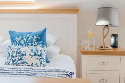 a bed with a blue and white pillow and a lamp at Carbis Bay - Luxury 3 Bed Penthouse Apartment with Sea Views Parking Sauna Balcony in Carbis Bay