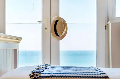 a hat hanging on a bed in front of a window at Carbis Bay - Luxury 3 Bed Penthouse Apartment with Sea Views Parking Sauna Balcony in Carbis Bay
